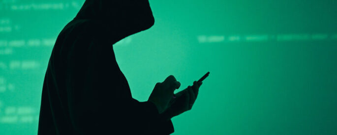 Silhouette of man in hoodie hacking a phone